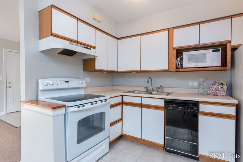 Kitchen with white oak-trimmed cabinets, white stove, black dishwasher and a microwave, Park Avenue apartment 603-206