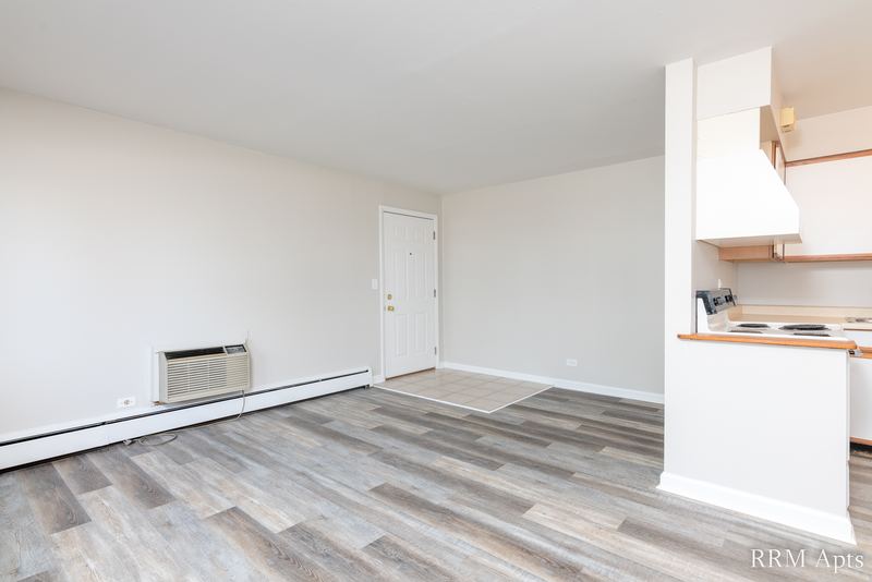 Living room with wood-look floor, wall air conditioner and a view into the kitchen, Park Avenue apartment 607 101