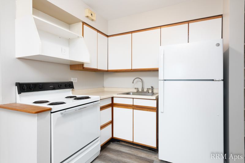 Kitchen with white oak-trimmed cabinets, white stove, white refrigerator and a double sink, Park Avenue apartment 607 101