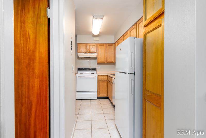 Kitchen with oak cabinets, white stove and refrigerator, tile floor and an oak door, Park Avenue apartment 607 103