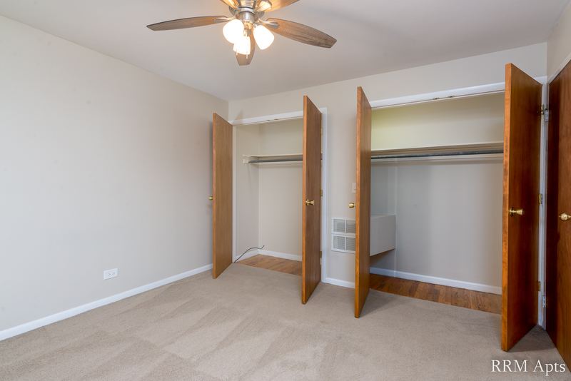 Bedroom with beige carpet, ceiling fan, two open closets and an oak door, Park Avenue apartment 607 103