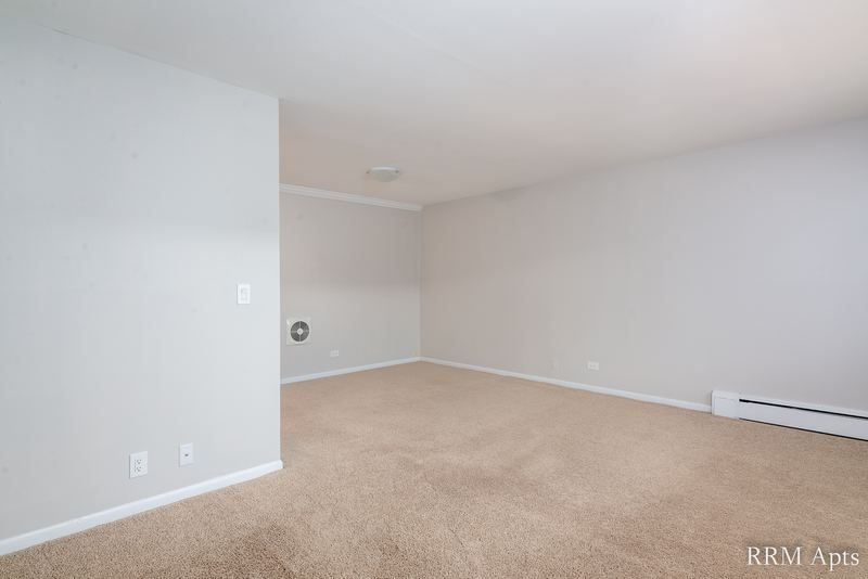 Empty room with beige carpet, gray walls, round wall vent and a baseboard heater, Park Avenue apartment 607 203