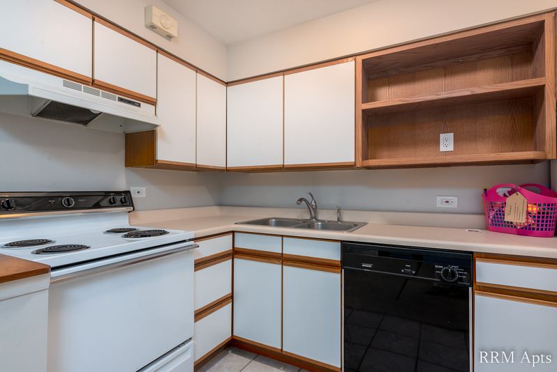 Kitchen with white oak-trimmed cabinets, white stove, black dishwasher and open shelves, Park Avenue apartment 607 203