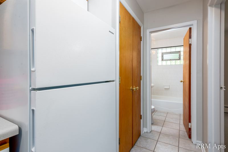 Hallway with white refrigerator, oak door, tile floor and a view into the bathroom, Park Avenue apartment 607 203