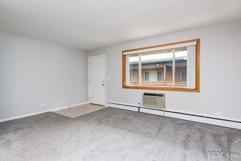 Living room with gray carpet, white entry door, tile entry, window and wall air conditioner, Park Avenue apartment 607 204