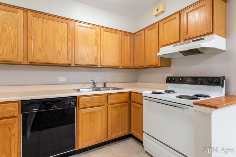 Kitchen with oak cabinets, black dishwasher, white stove, range hood and a double sink, Park Avenue apartment 607 204