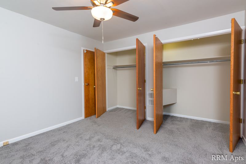 Bedroom with gray carpet, ceiling fan, two open closets and an oak door, Park Avenue apartment 607 204