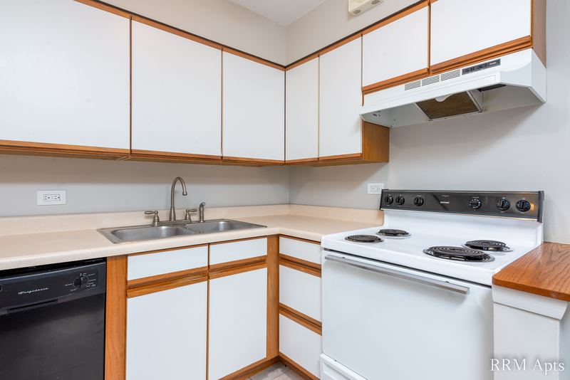 Kitchen with white oak-trimmed cabinets, white stove, black dishwasher and a range hood, Park Avenue apartment 607 206