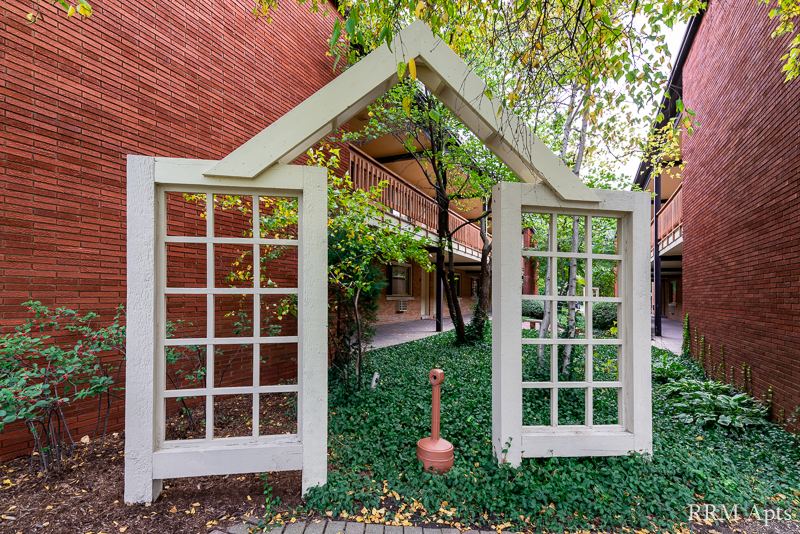 Landscaped courtyard with a white trellis between brick apartment buildings, Park Avenue, Libertyville
