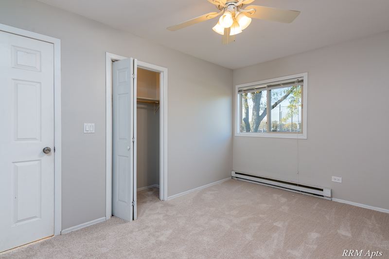 Bedroom with beige carpet, ceiling fan, white door, open closet and a window, Park West apartment 611 C