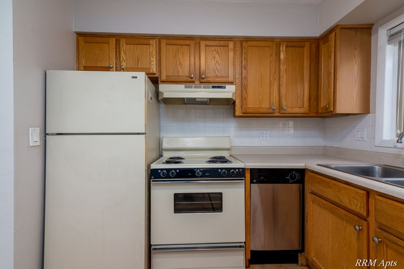 Kitchen with oak cabinets, white refrigerator, electric stove and stainless dishwasher, Park West apartment 611 C