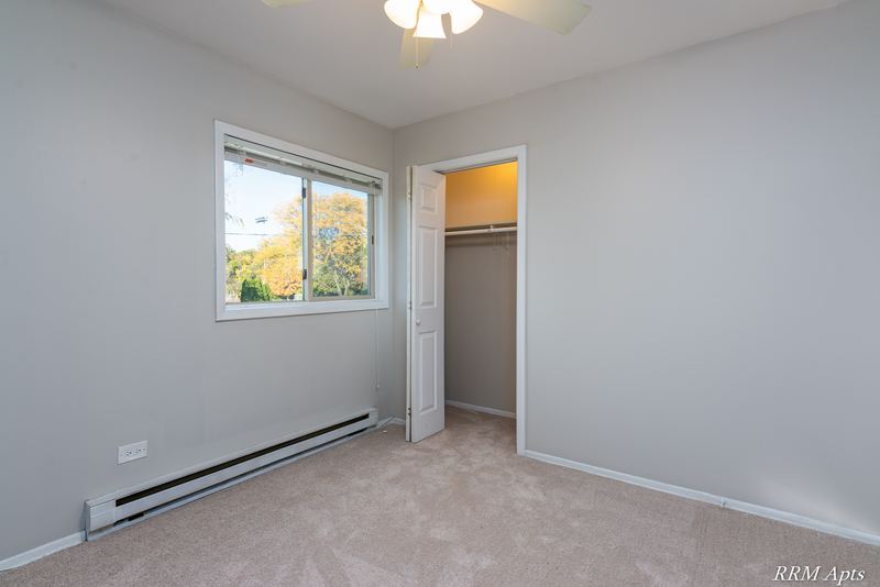 Bedroom with beige carpet, ceiling fan, window and an open closet, Park West apartment 611 C