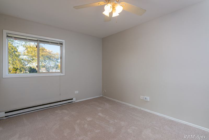 Bedroom with beige carpet, ceiling fan, gray walls and a window with trees, Park West apartment 611 C