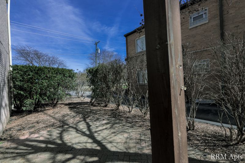 Patio with brick pavers, hedges and a view of the neighboring brick building, Park West apartment 611A