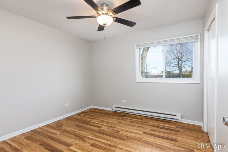 Bedroom with wood floor, ceiling fan, window and a baseboard heater, Park West apartment 611A