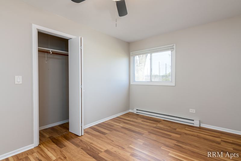 Bedroom with wood floor, open closet, window and a baseboard heater, Park West apartment 611A