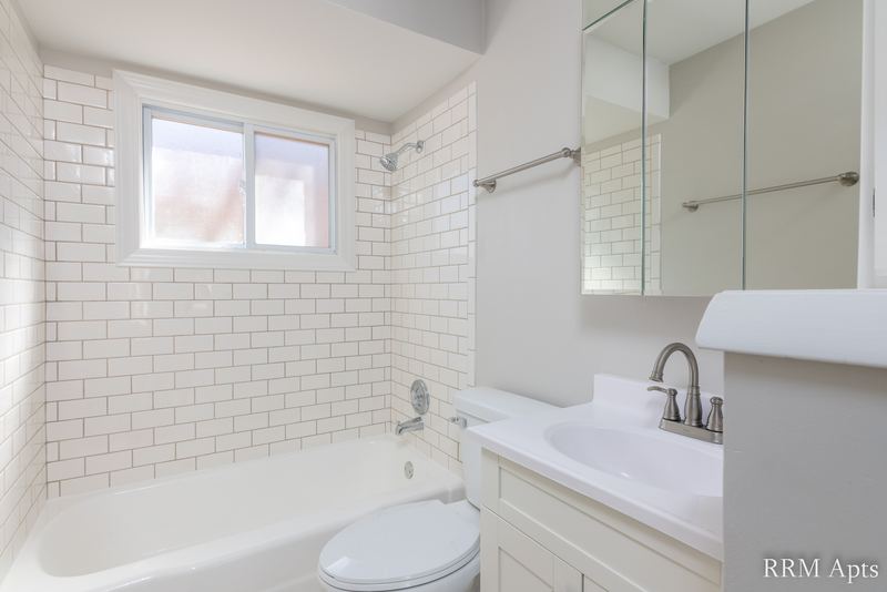 Bathroom with white subway tile tub surround, small window, white vanity and mirrored cabinet, Park West apartment 611A