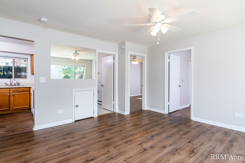 Living room with wood-look floor, ceiling fan, kitchen pass-through and hallway doorways, Park West apartment 613 B