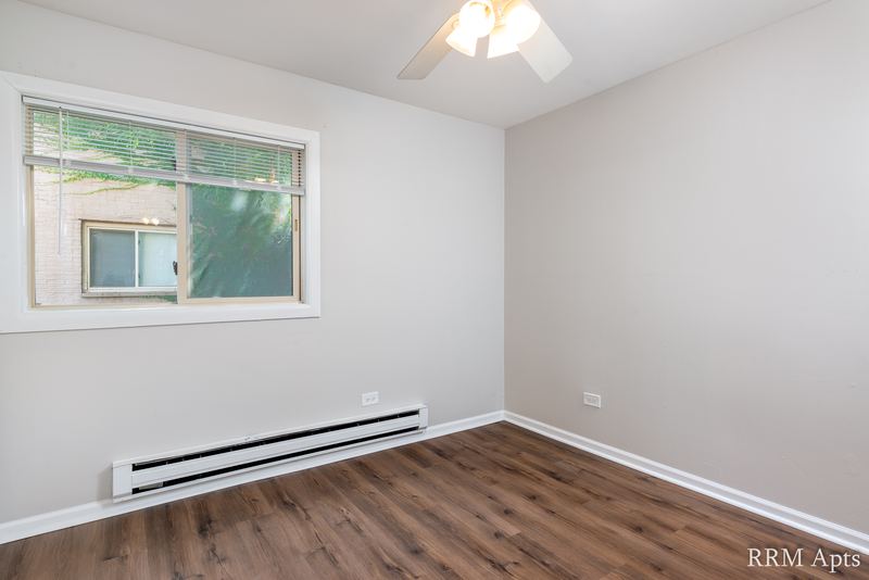 Bedroom with wood-look floor, ceiling fan, gray walls and a window with a tree outside, Park West apartment 613 B