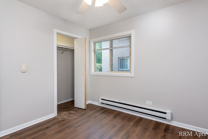 Bedroom with wood-look floor, ceiling fan, open closet, window and a baseboard heater, Park West apartment 613 B