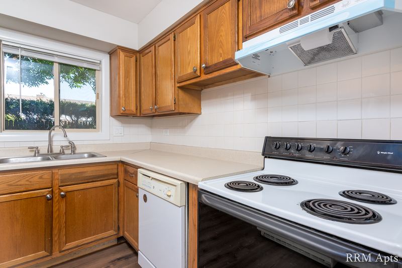 Kitchen with oak cabinets, sink window, white dishwasher, electric stove and tile backsplash, Park West apartment 613 B