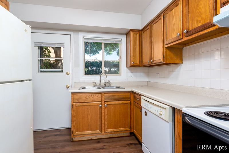 Kitchen with oak cabinets, white refrigerator and dishwasher, black stove and a sink window, Park West apartment 613 B