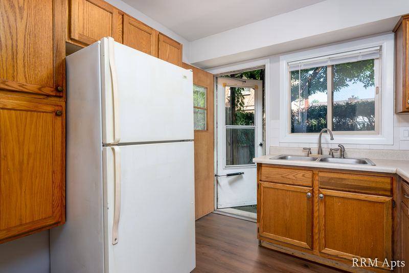 Kitchen with oak cabinets, white refrigerator, wood-look floor and a glass-paned back door, Park West apartment 613 B