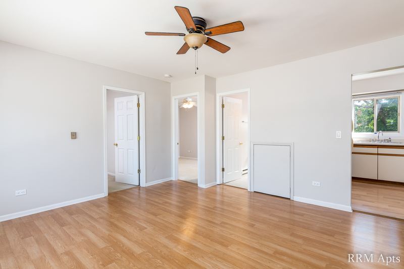 Living room with wood floor, ceiling fan, doorways to the bedrooms and a view into the kitchen, Park West apartment 613 C