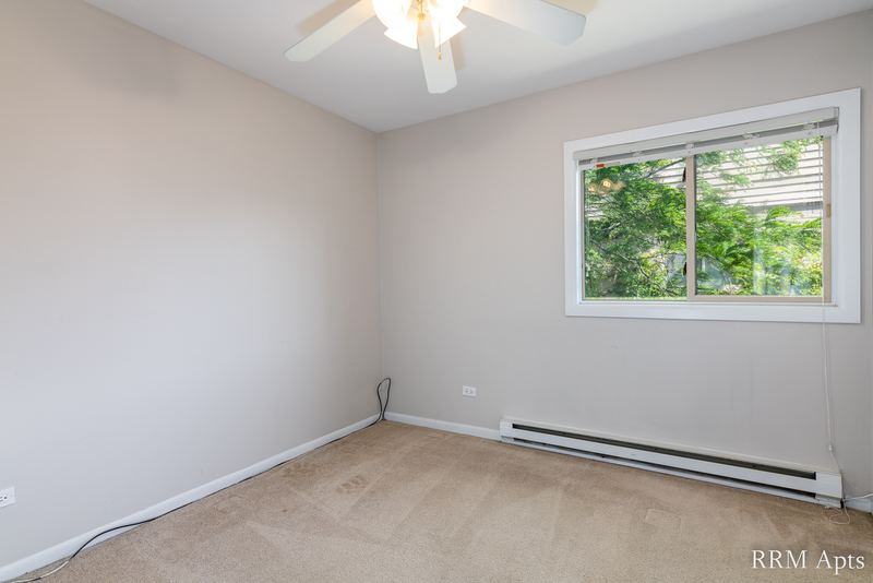 Bedroom with beige carpet, ceiling fan, window with trees and a baseboard heater, Park West apartment 613 C