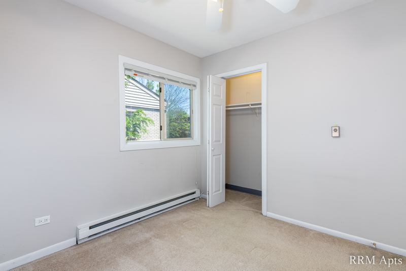Bedroom with beige carpet, ceiling fan, window, open closet and a baseboard heater, Park West apartment 613 C