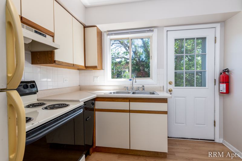 Kitchen with white cabinets, white refrigerator, black-and-white stove and a glass-paned door, Park West apartment 613 C