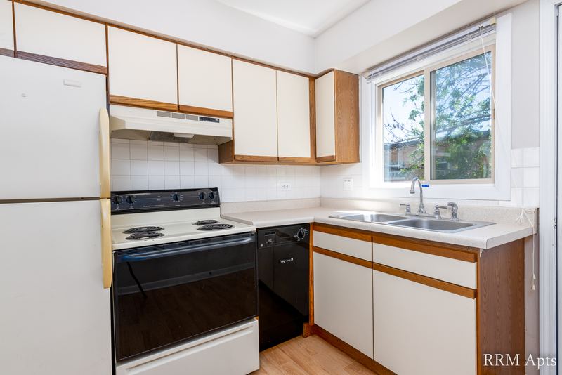 Kitchen with white oak-trimmed cabinets, white stove, black dishwasher and a sink window, Park West apartment 613 C