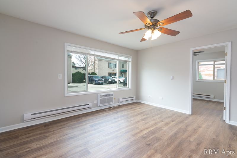 Living room with wood-look floor, ceiling fan, parking lot window and a doorway to the kitchen, Park West apartment 615 A