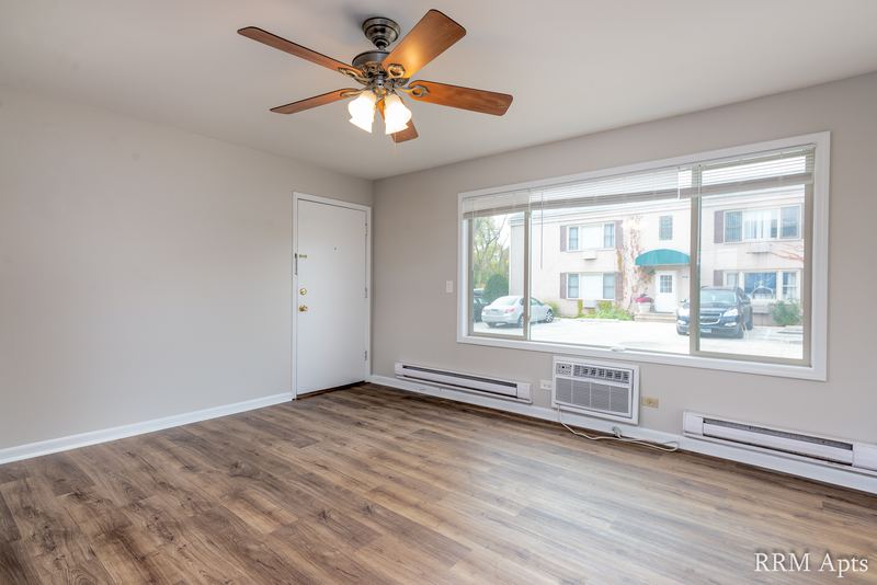 Living room with wood-look floor, ceiling fan, entry door, window and a wall air conditioner, Park West apartment 615 A