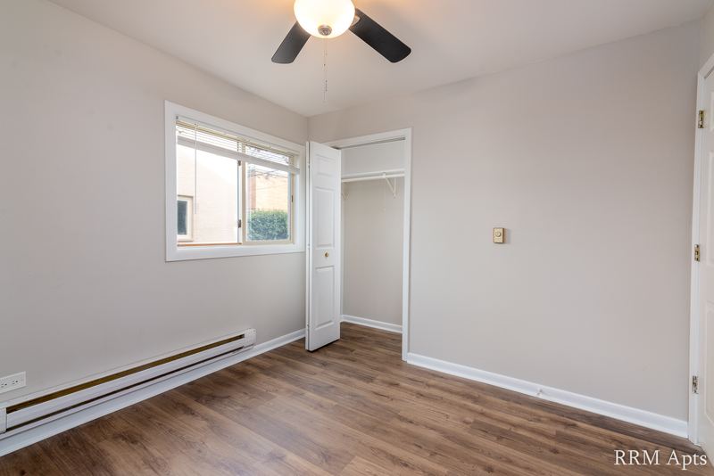 Bedroom with wood-look floor, ceiling fan, small window, open closet and a baseboard heater, Park West apartment 615 A