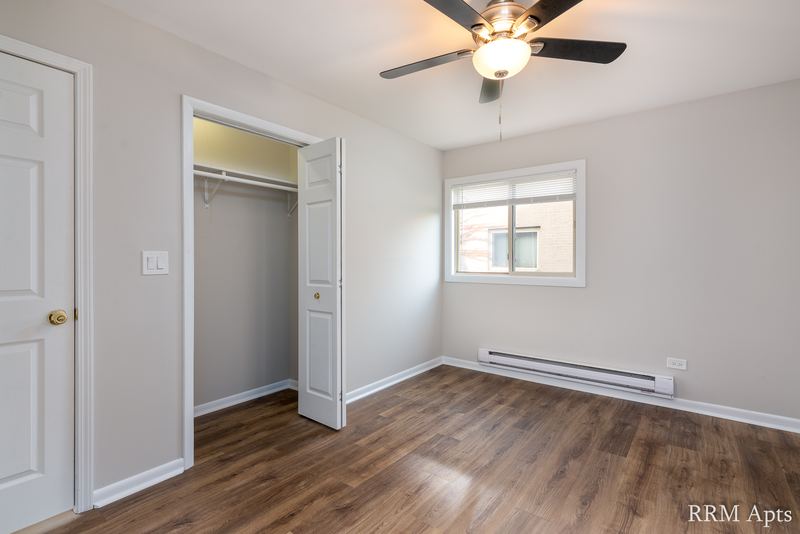 Bedroom with wood-look floor, ceiling fan, white door, open closet and a window, Park West apartment 615 A