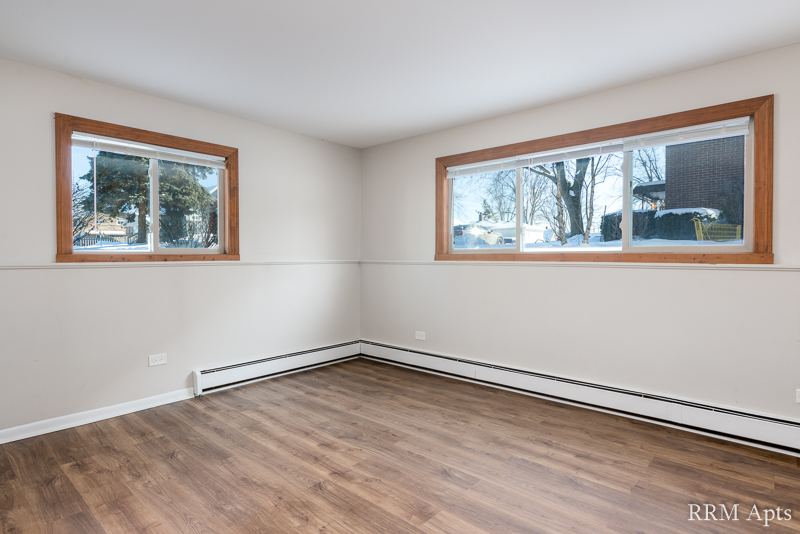 Bedroom with two windows, baseboard heater and wood-look floor, Pioneer Court apartment 900-1A