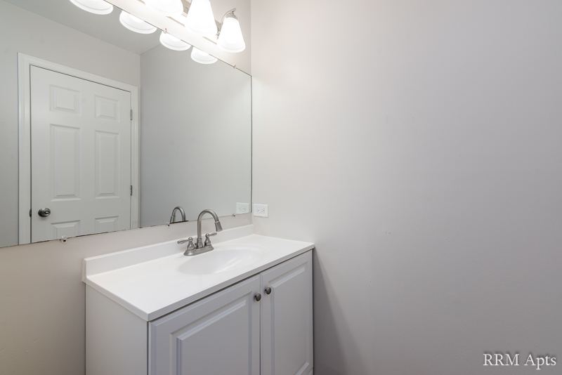 Bathroom with white vanity and large mirror, Pioneer Court apartment 900-1A