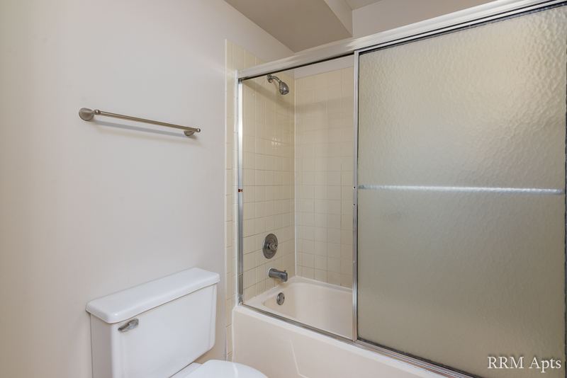 Bathroom with tub and shower behind sliding glass doors, Pioneer Court apartment 900-1A