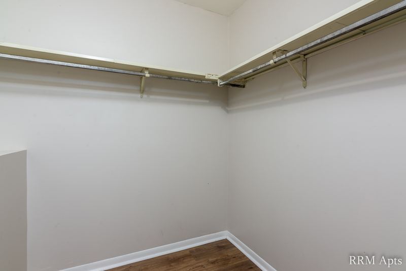 Closet with wood-look floor, gray walls and a long shelf with a hanging rod, Pioneer Court apartment 900 1D