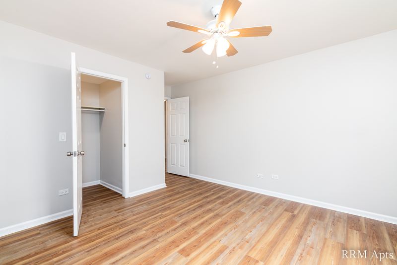 Bedroom with wood-look floor, ceiling fan, open closet and white doors, Pioneer Court apartment 900 2A