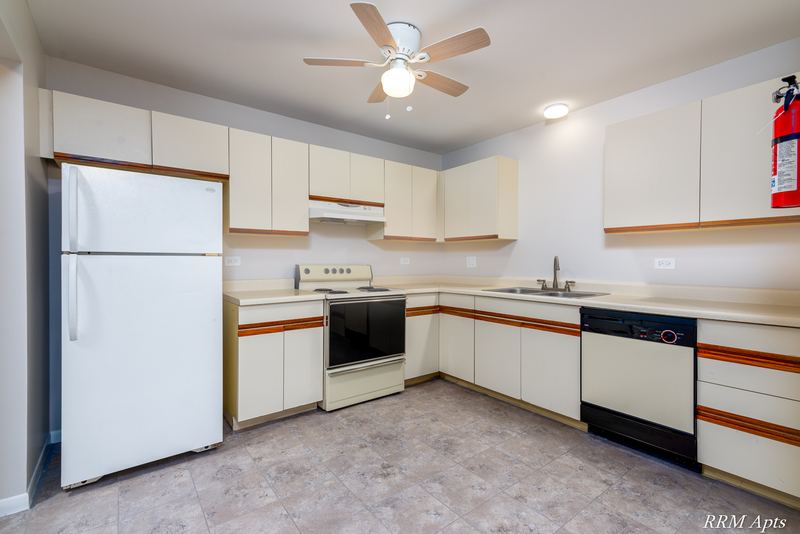 Kitchen with white oak-trimmed cabinets, white appliances, gray floor and a ceiling fan, Pioneer Court apartment 900 2E