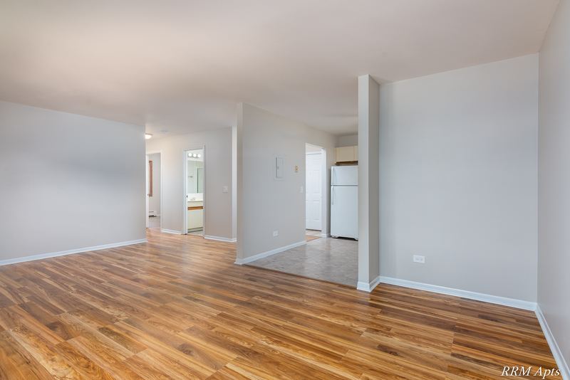 Living room with wood-look floor, a half wall and a hallway leading to the kitchen, Pioneer Court apartment 900 2E