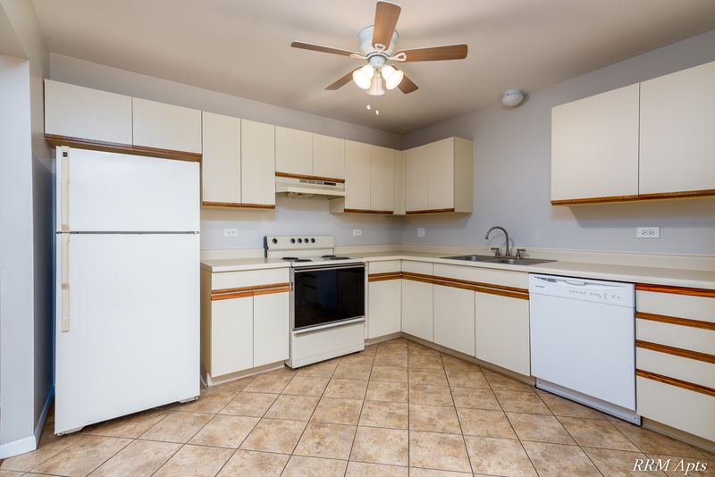Kitchen with white oak-trimmed cabinets, white appliances, tile floor and a ceiling fan, Pioneer Court apartment 900 3A