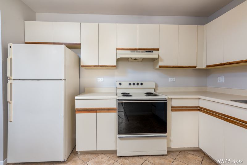 Kitchen with white oak-trimmed cabinets, white refrigerator, white stove and a range hood, Pioneer Court apartment 900 3A