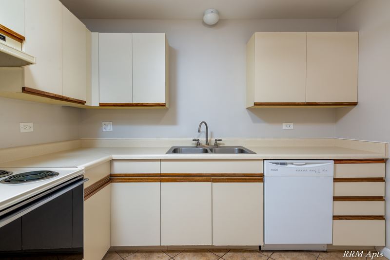 Kitchen with white oak-trimmed cabinets, black stove, double sink and white dishwasher, Pioneer Court apartment 900 3A