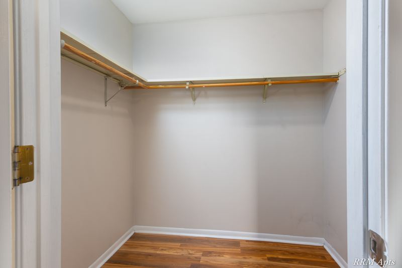 Closet with wood-look floor, white door and a long shelf with a hanging rod, Pioneer Court apartment 900 3A
