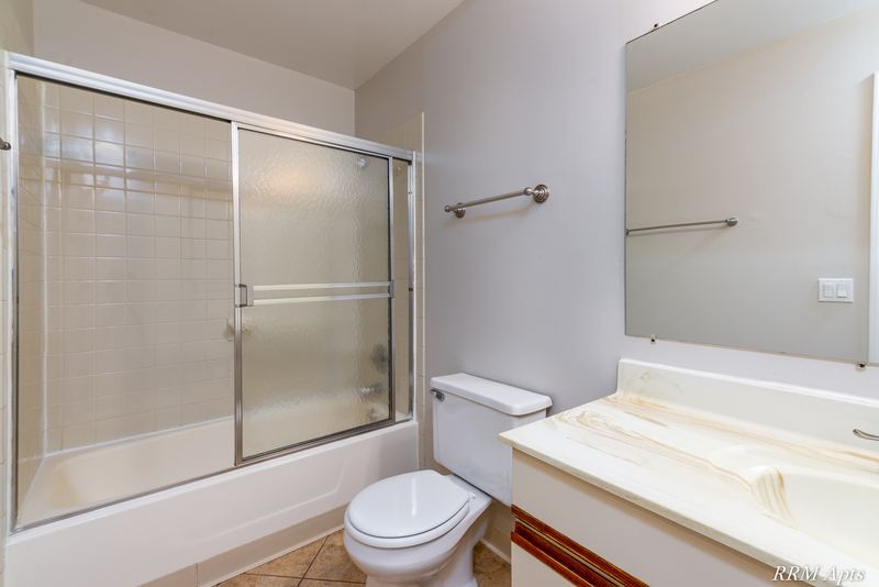 Bathroom with sliding glass tub doors, cream vanity, toilet and a towel bar, Pioneer Court apartment 900 3A