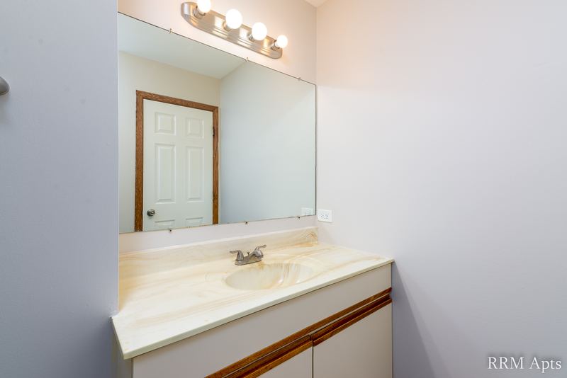 Bathroom with cream vanity, wide mirror, light bar and an oak door, Pioneer Court apartment 900 3C