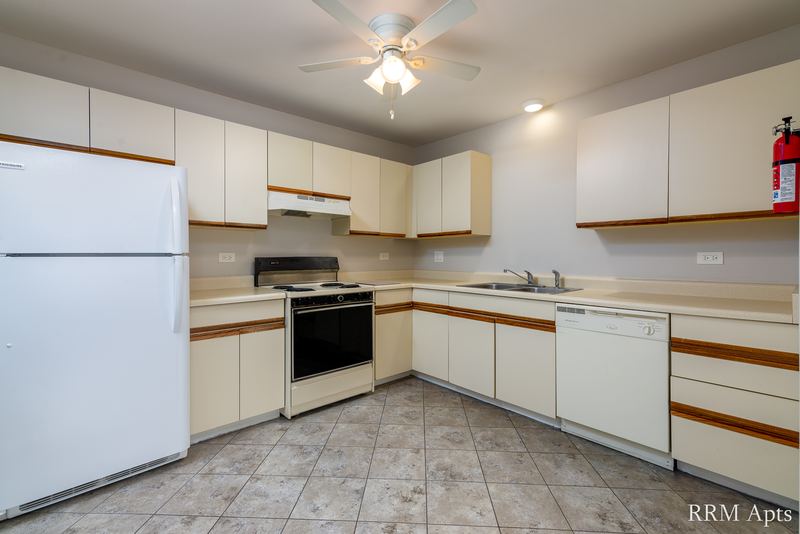 Kitchen with white oak-trimmed cabinets, white appliances, ceiling fan and tile floor, Pioneer Court apartment 900 3C